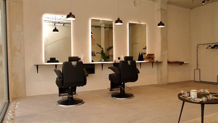 Barbería con sillones de cuero y espejos retroiluminados