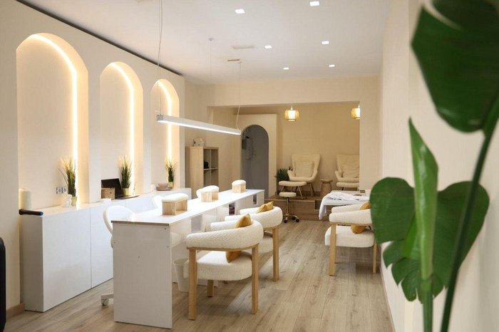 Salón de uñas con mesas y sillones blancos